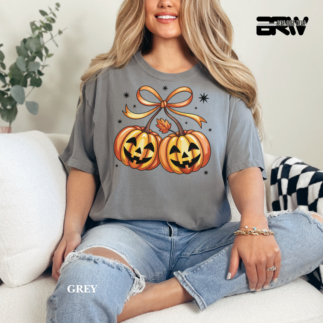 Woman wearing a gray t-shirt with Halloween-themed design sitting on a couch.