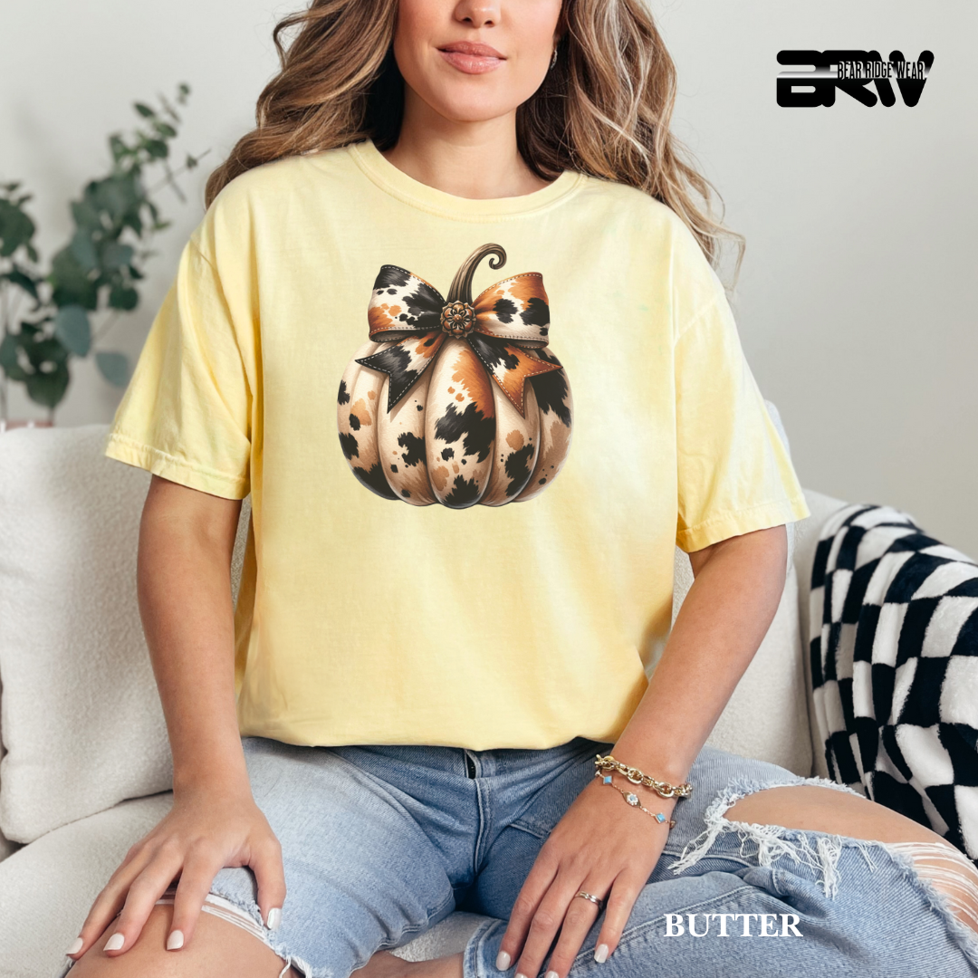 Person wearing a yellow t-shirt with a pumpkin design, sitting on a couch.