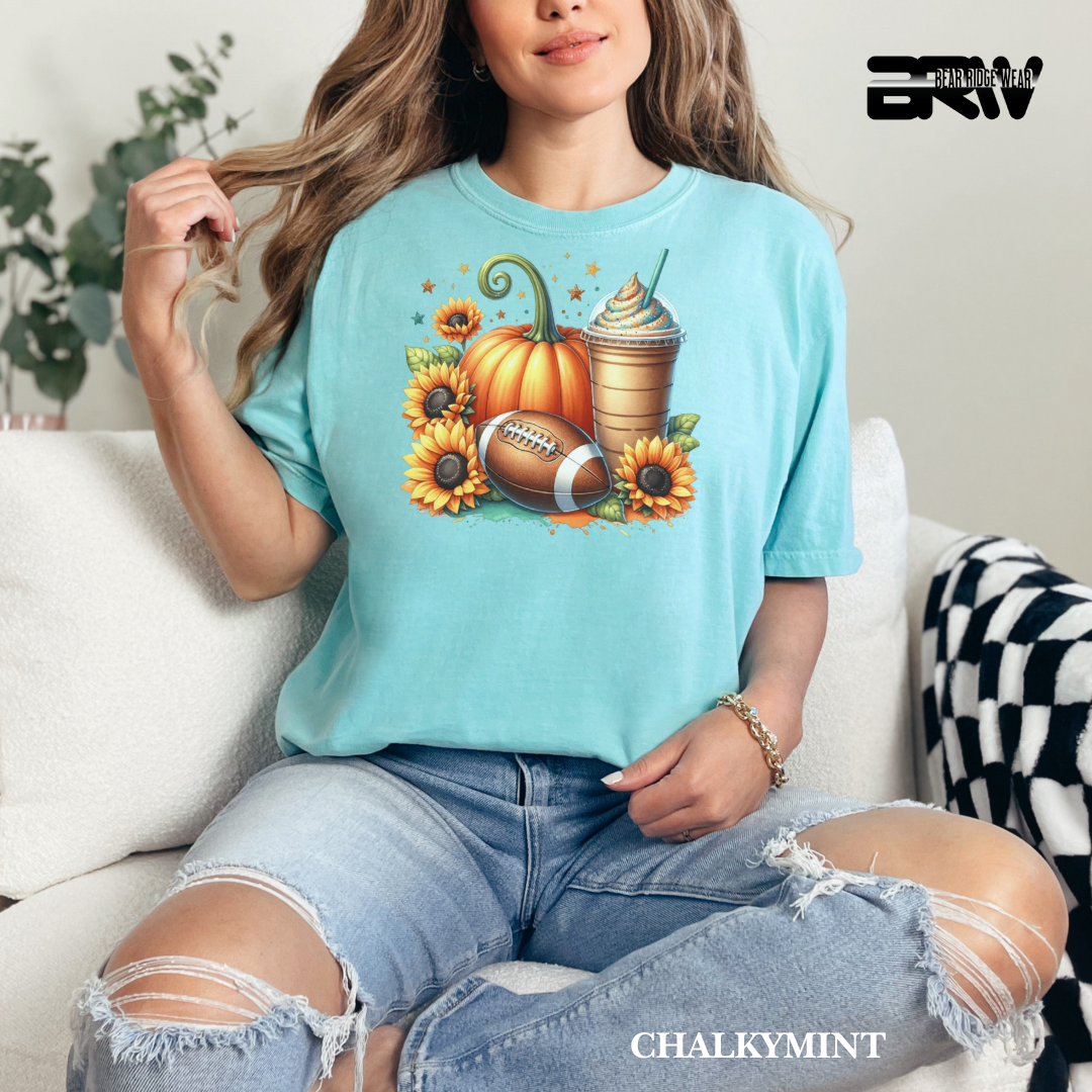 Woman wearing a light blue t-shirt with autumn-themed design, sitting on a couch.