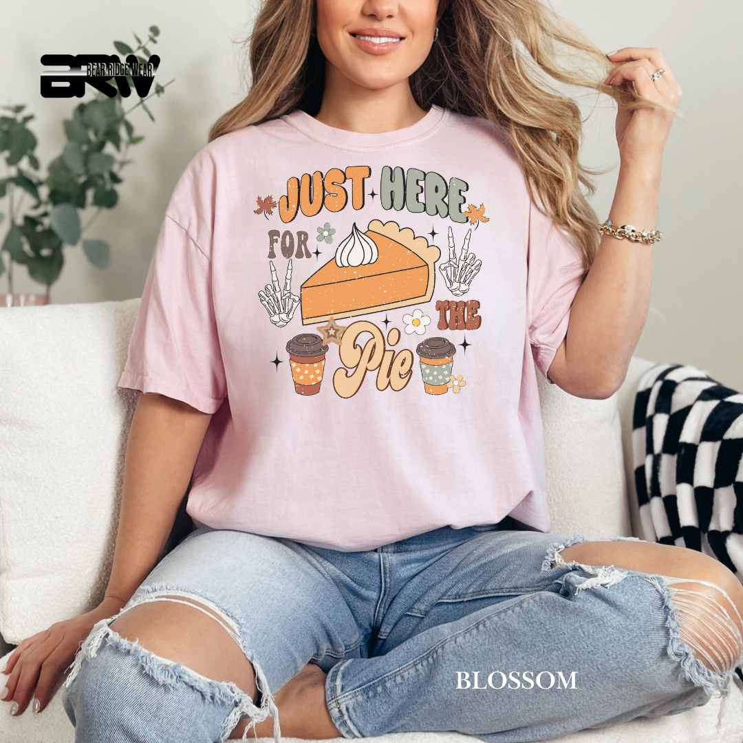 Woman wearing a pink t-shirt with a pie and coffee design, sitting on a couch.