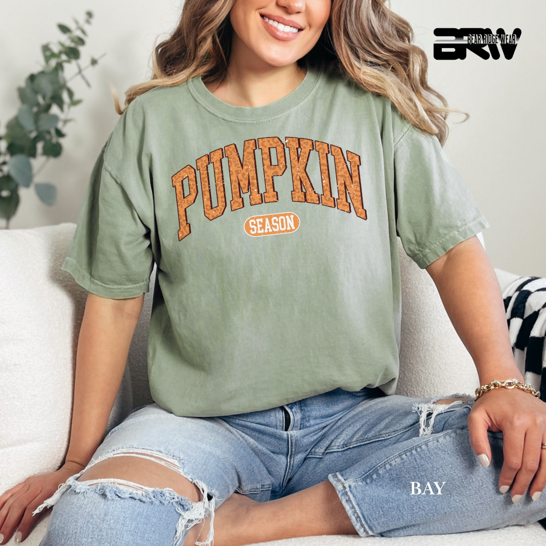 Person wearing a bay t-shirt with 'Pumpkin Season' text, sitting on a couch.