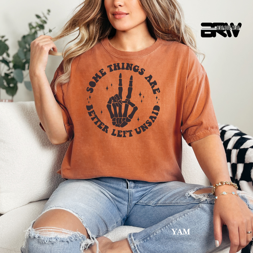 Person wearing a brown t-shirt with a skeleton hand design and text, sitting on a couch.