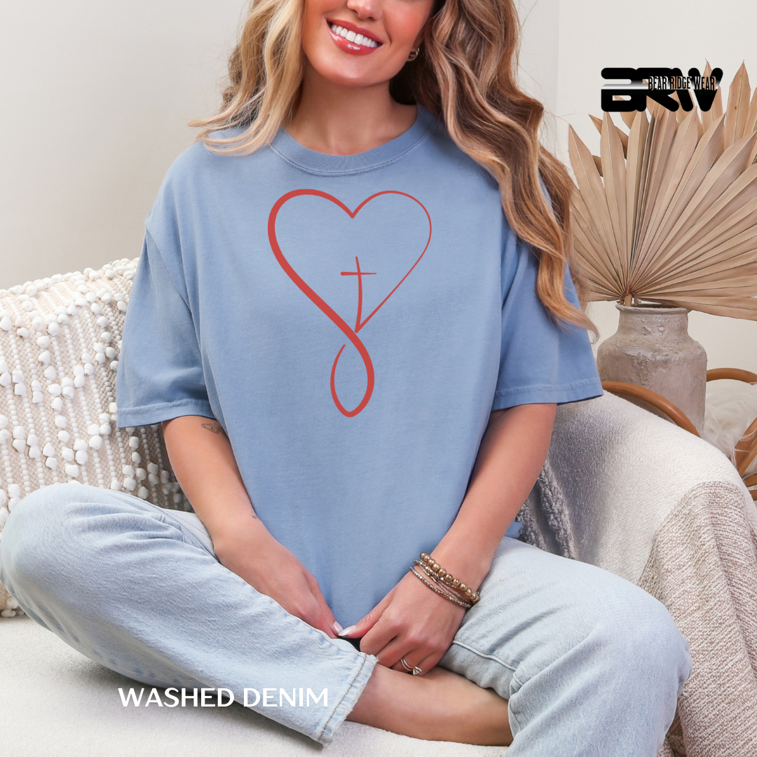 Woman wearing a blue t-shirt with a red heart design, sitting on a couch.