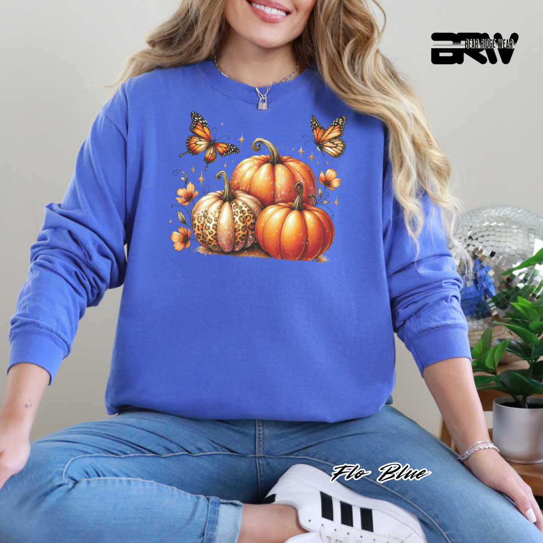 Person wearing a blue sweatshirt with pumpkins and butterflies design, sitting indoors.