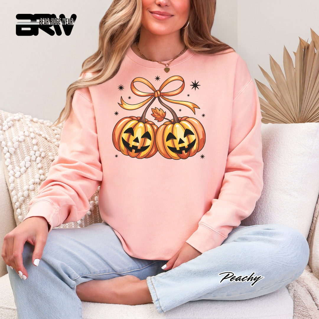 Person wearing a pink sweatshirt with Halloween-themed design sitting on a couch.