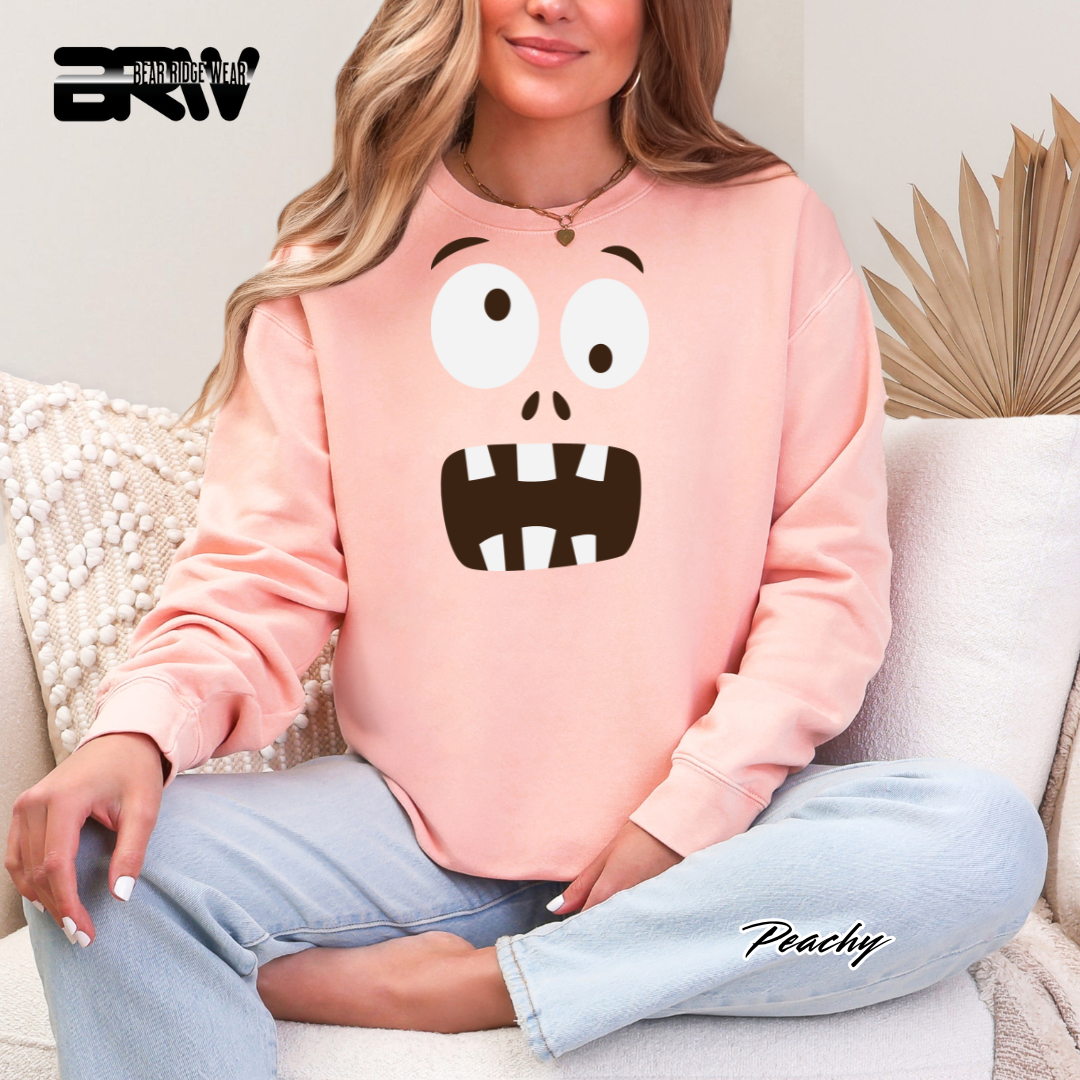 Person wearing a pink sweatshirt with a cartoon character design, sitting on a couch.