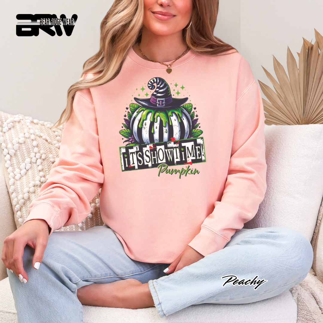 Person wearing a pink sweatshirt with a Halloween-themed design, sitting on a couch.