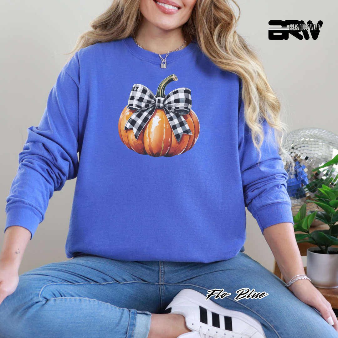 Person wearing a blue sweatshirt with a pumpkin design, sitting indoors.