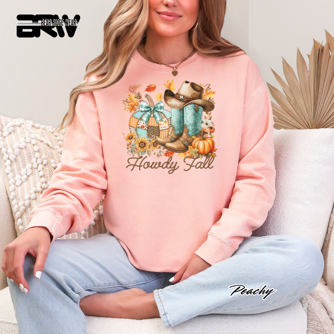 Person wearing a pink sweatshirt with 'Howdy Fall' design, sitting on a couch.
