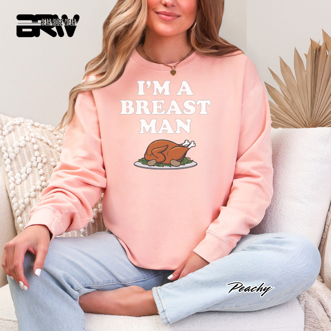 Person wearing a pink sweatshirt with 'I'm a Breast Man' text and turkey graphic, sitting on a couch.