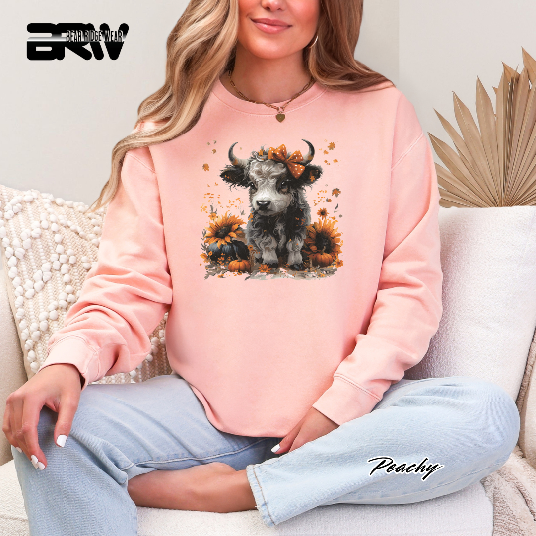 Person wearing a pink sweatshirt with a graphic design of a COW and flowers, sitting on a couch.