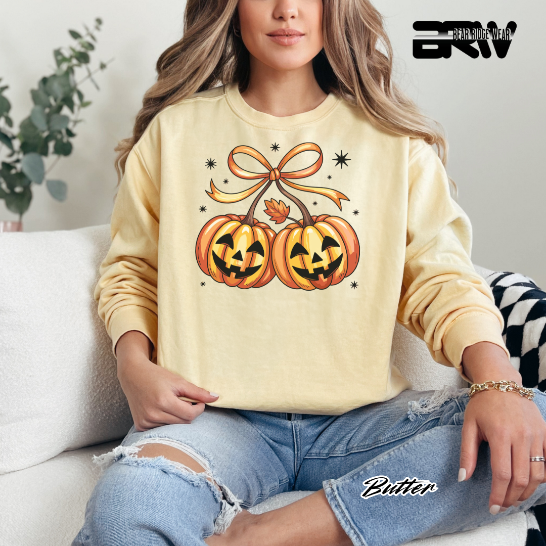 Person wearing a beige sweatshirt with Halloween-themed design sitting on a couch.