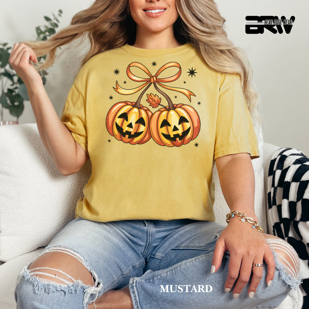 Woman wearing a mustard yellow t-shirt with Halloween-themed design, sitting on a couch.