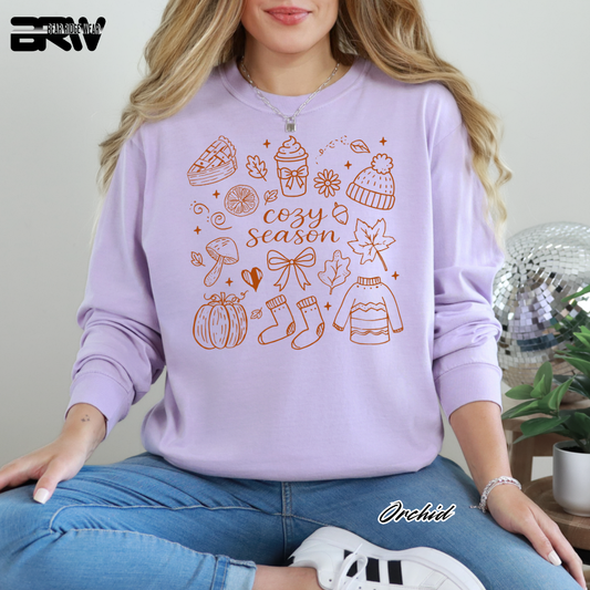 Person wearing a purple sweatshirt with autumn-themed graphics and text.