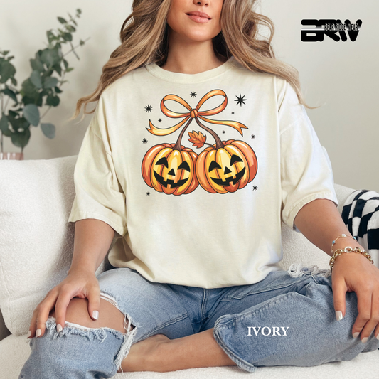 Person wearing a white sweatshirt with pumpkin design sitting on a couch.