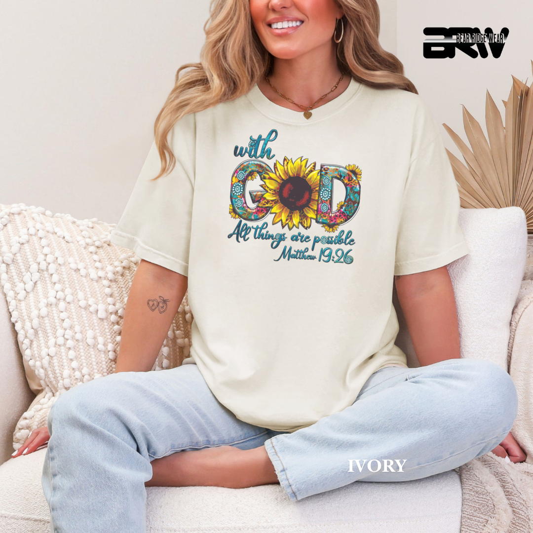 Woman wearing a white t-shirt with a sunflower graphic and text, sitting on a couch.