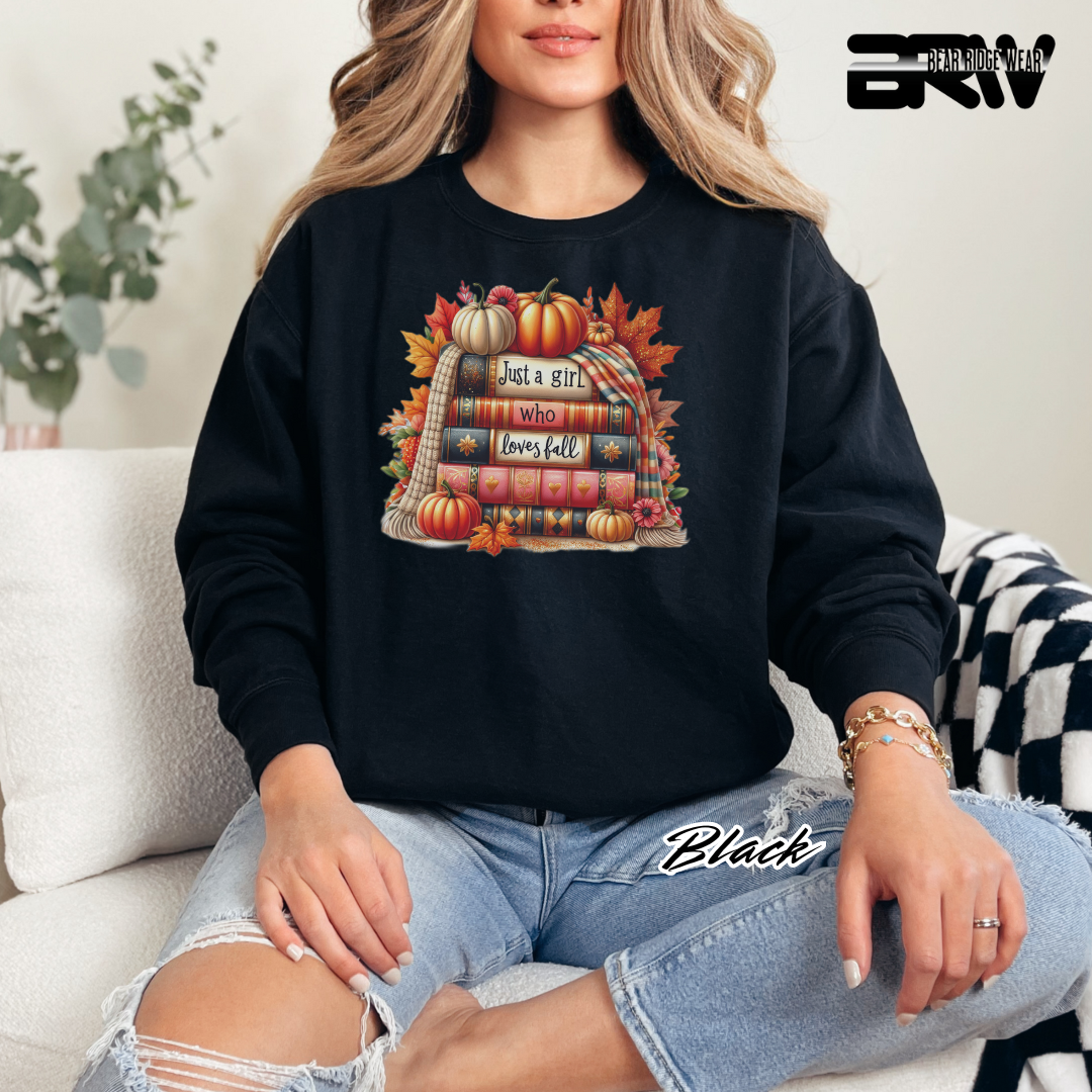 Person wearing a black sweatshirt with a fall-themed design, sitting on a couch.