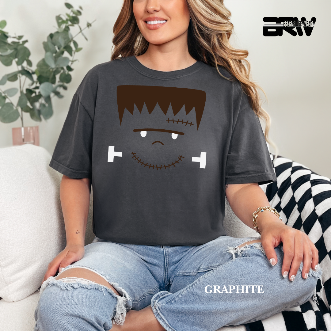 Person wearing a graphite t-shirt with a graphic design, sitting on a couch.
