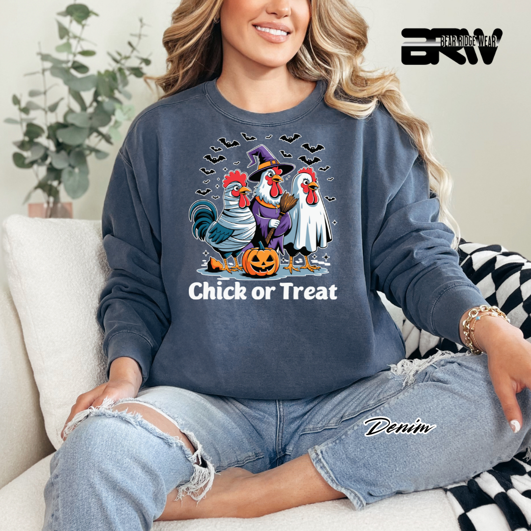 Person wearing a denim sweatshirt with Halloween-themed rooster design, sitting on a couch.