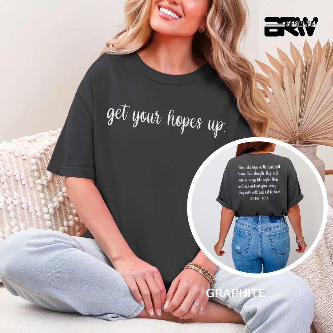Person wearing a black t-shirt with 'get your hopes up' text, sitting on a couch.
