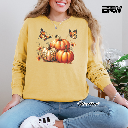 Person wearing a yellow sweatshirt with pumpkins and butterflies design, sitting indoors.