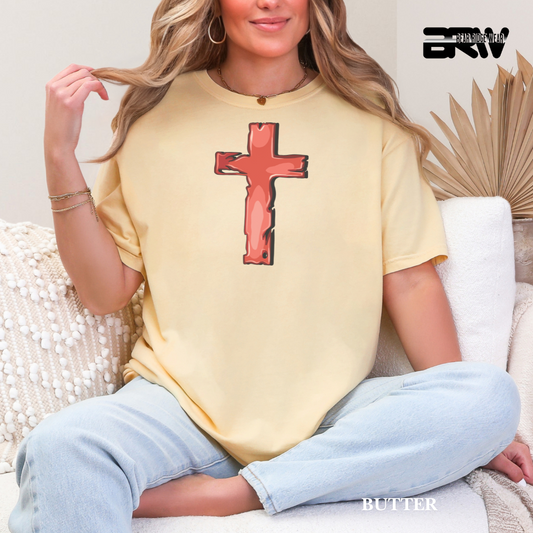Woman wearing a yellow t-shirt with a red cross design, sitting on a couch.