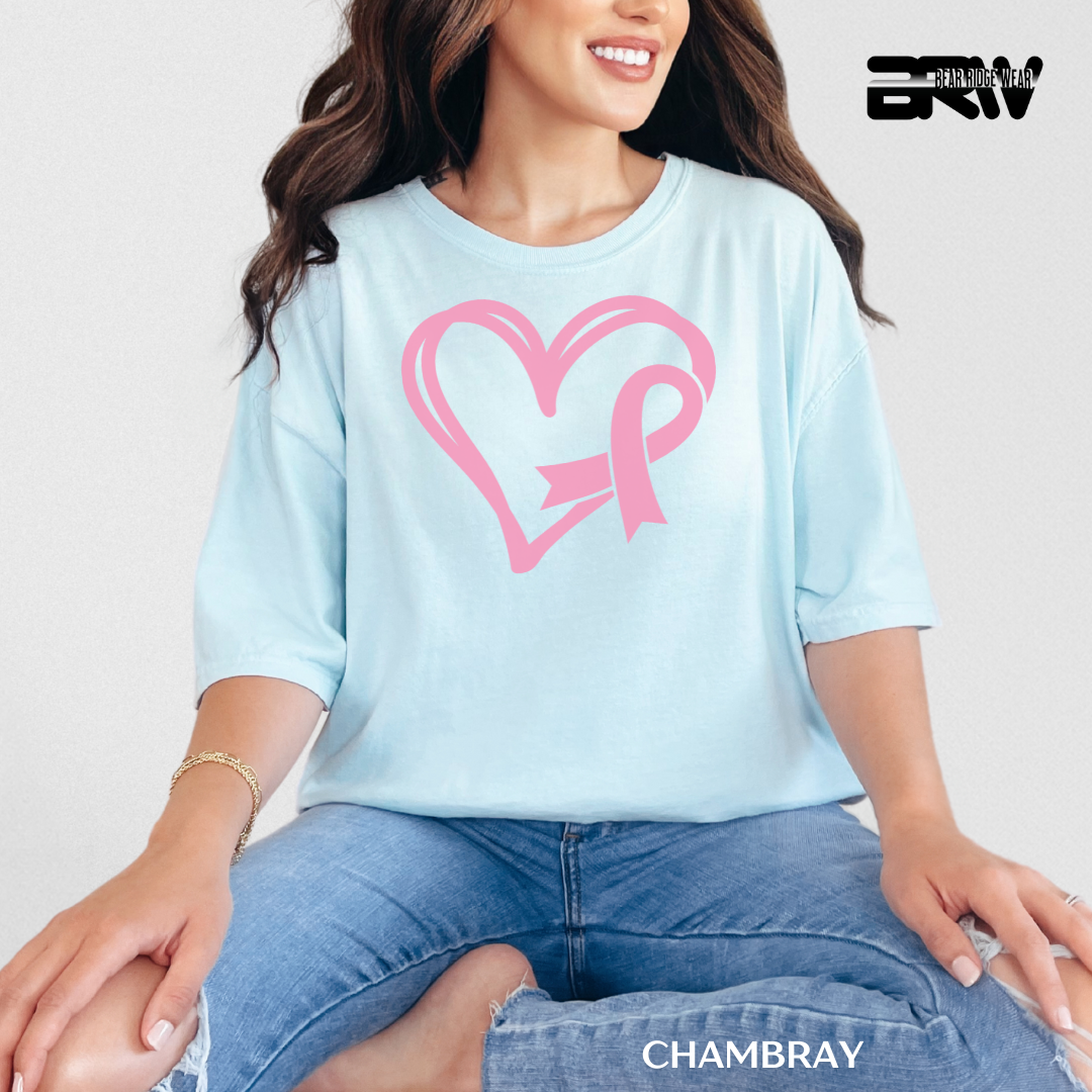 Woman wearing a light blue shirt with a pink heart and bow design, sitting against a plain background.