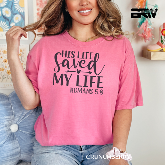 Woman wearing a pink t-shirt with text, sitting on a couch. FAITH TEE