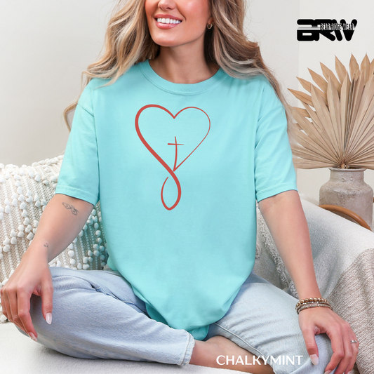 Woman wearing a light blue t-shirt with a red heart and cross design, sitting on a couch.
