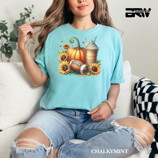 Woman wearing a light blue t-shirt with autumn-themed design, sitting on a couch.