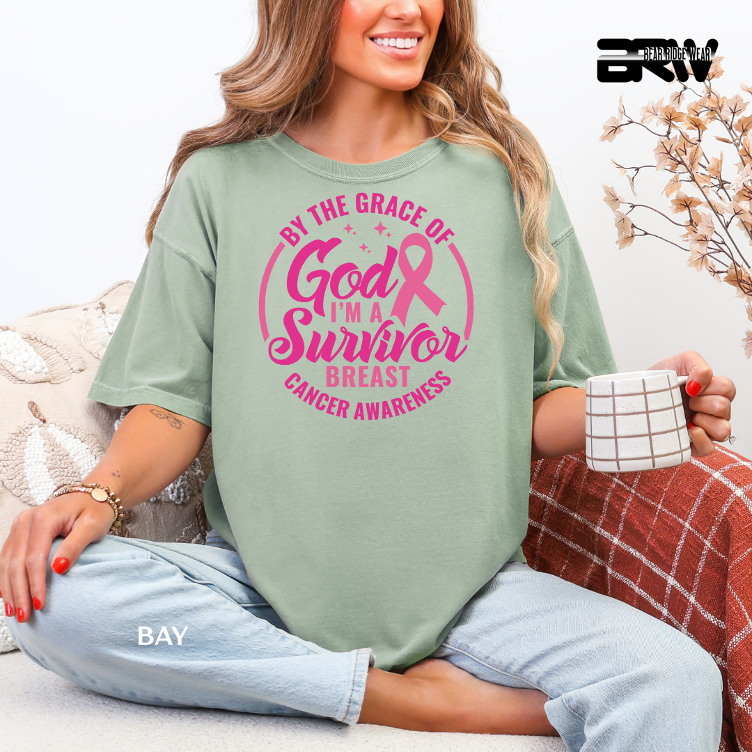 Woman wearing a green t-shirt with pink breast cancer awareness text, sitting on a couch.