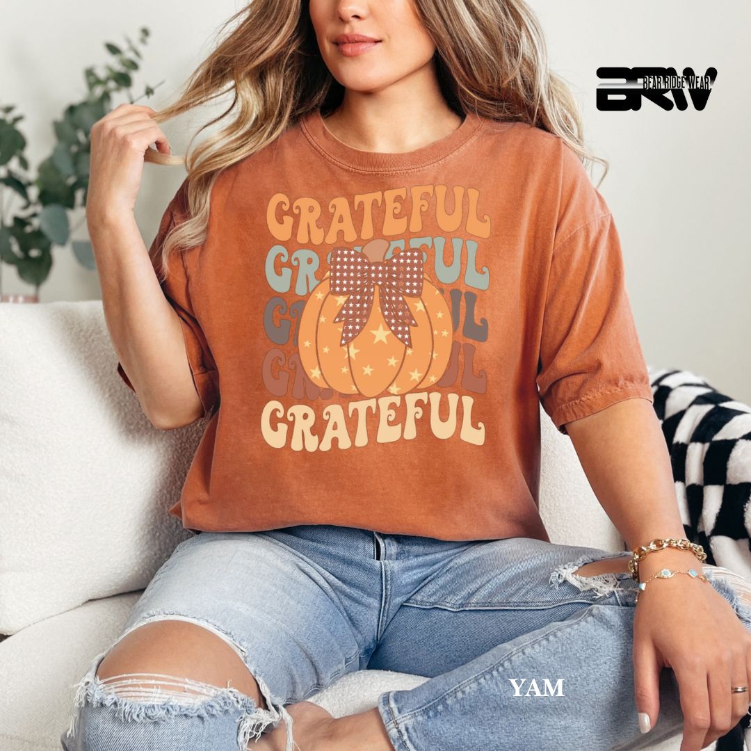 Person wearing a 'Grateful' t-shirt with pumpkins sitting on a couch.