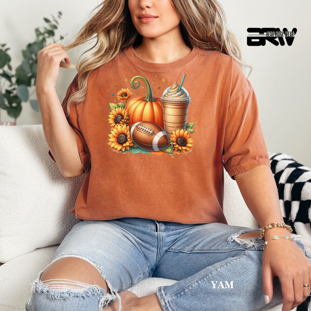 Person wearing a brown t-shirt with autumn-themed graphics sitting on a couch.