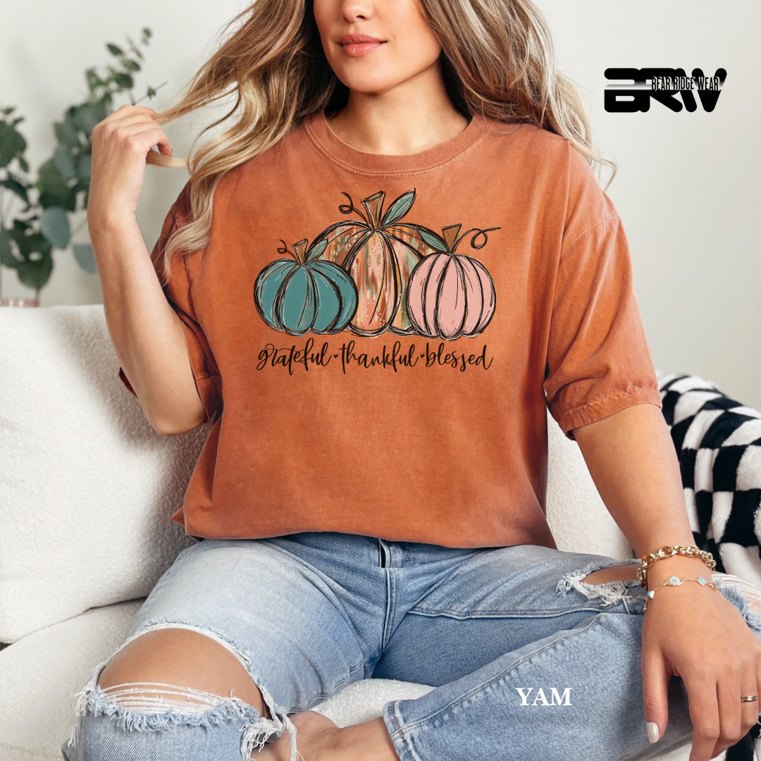 Person wearing a brown t-shirt with pumpkin design and text, sitting on a couch.