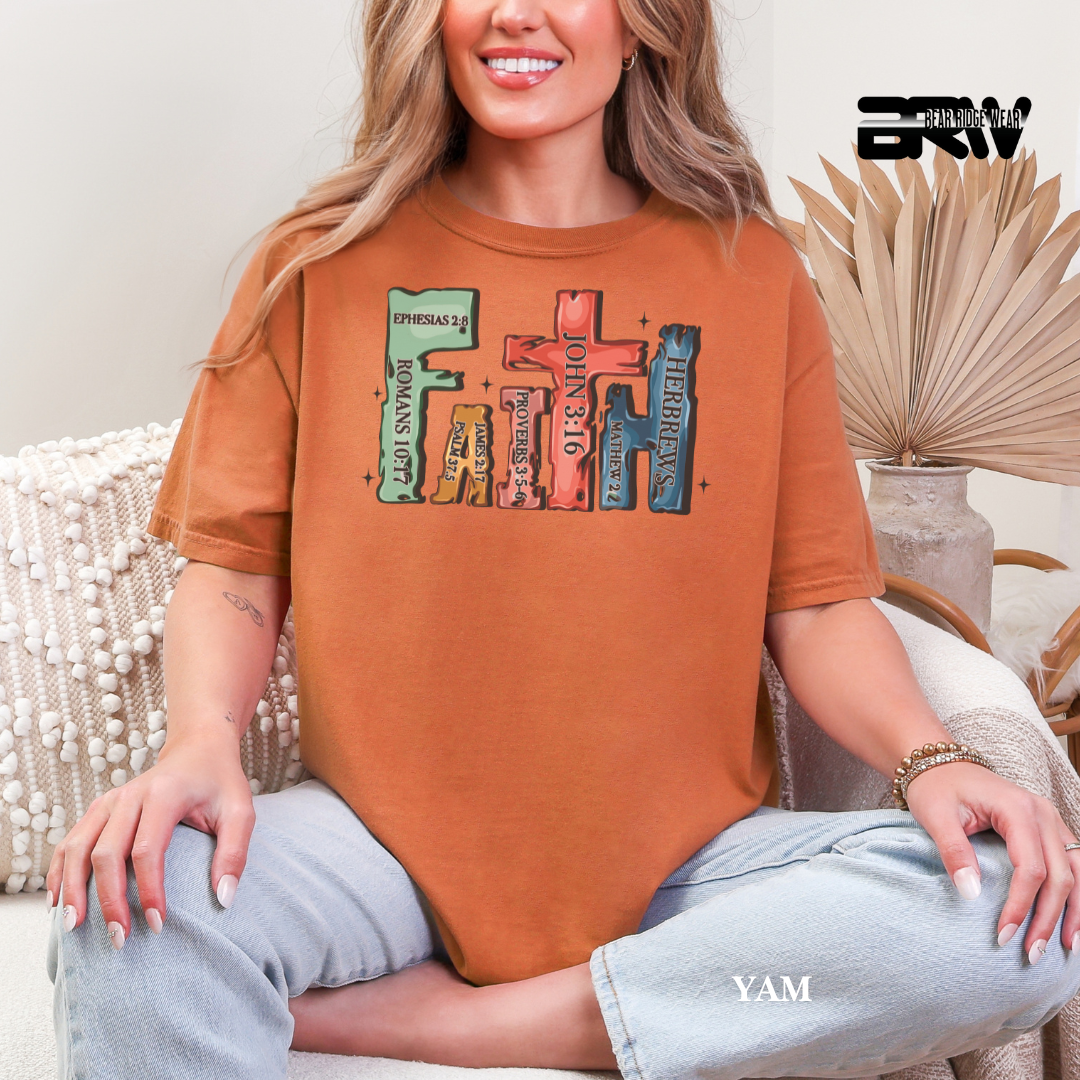Person wearing a brown t-shirt with colorful text design, sitting on a couch.