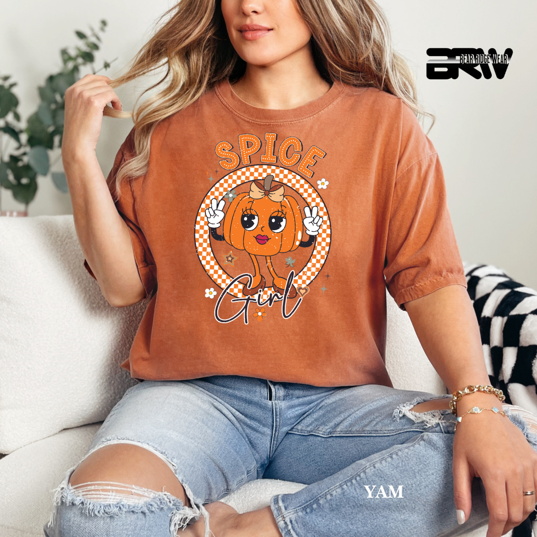 Person wearing a brown t-shirt with a pumpkin graphic and text, sitting on a couch.