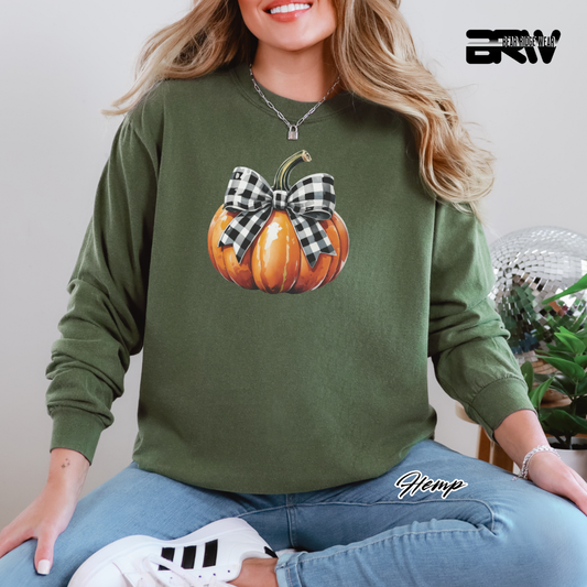 Person wearing a green sweatshirt with a pumpkin design, sitting indoors.