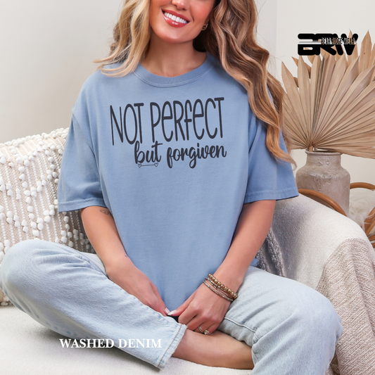 Woman wearing a blue t-shirt with 'Not Perfect but Forgiven' text, sitting on a couch.