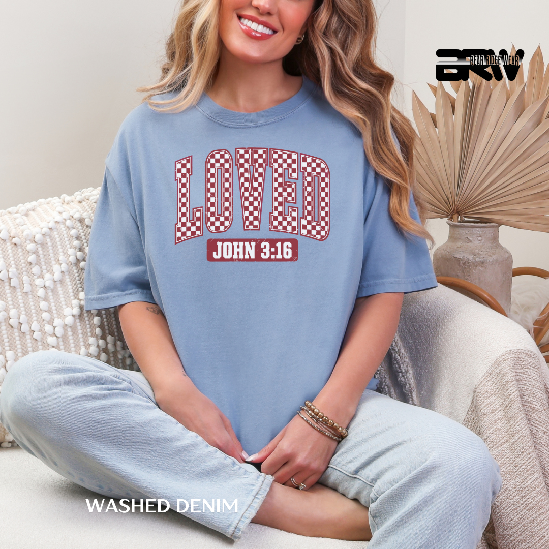 Woman wearing a blue t-shirt with 'LOVED John 3:16' text, sitting on a couch.