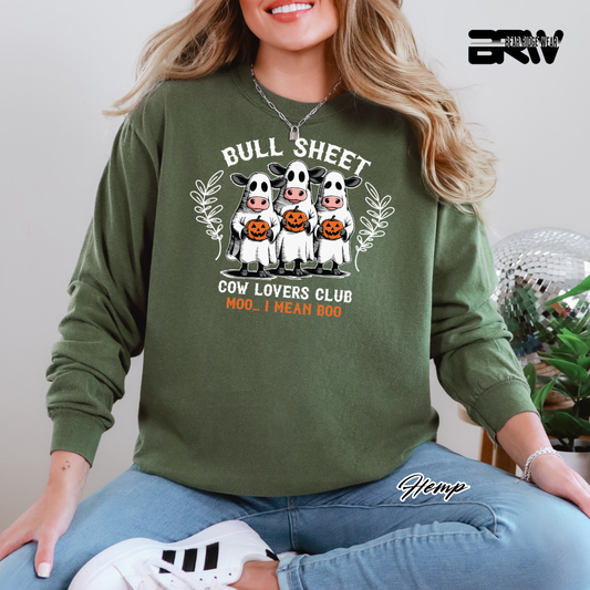 Person wearing a green sweatshirt with 'Bull Sheet Cow Lovers Club' design, sitting indoors.