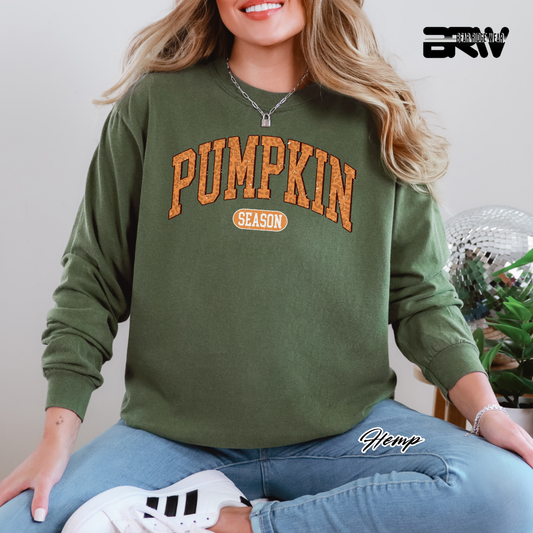 Person wearing a green sweatshirt with 'Pumpkin Season' text, sitting indoors.