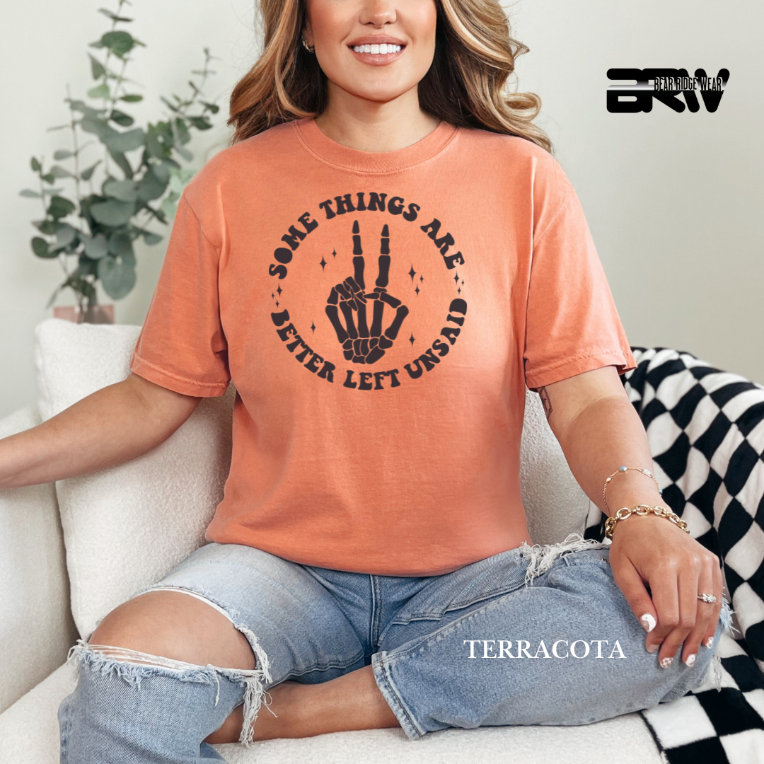 Person wearing a terracotta t-shirt with a graphic design, sitting on a couch. Fall graphic tee