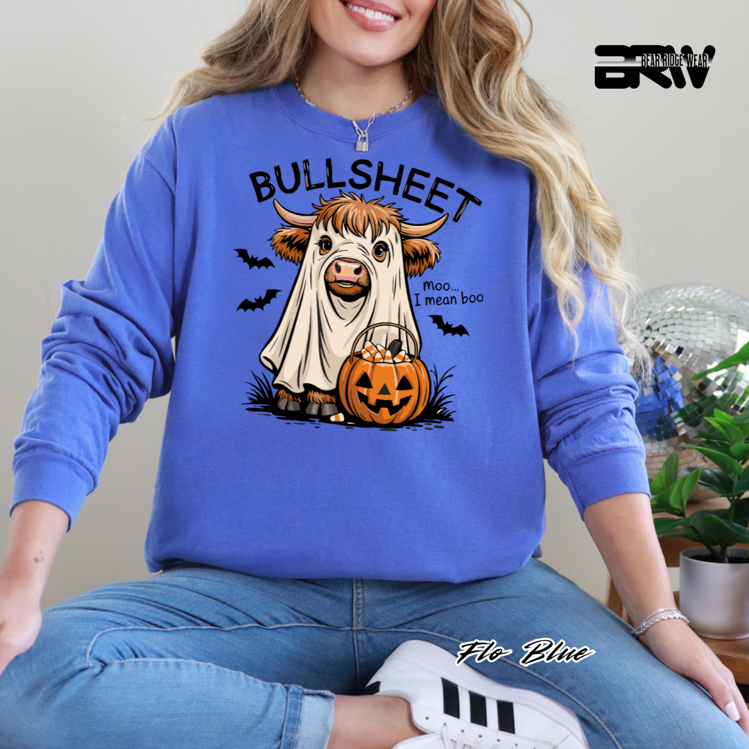Person wearing a blue sweatshirt with a cow graphic and text, sitting indoors.