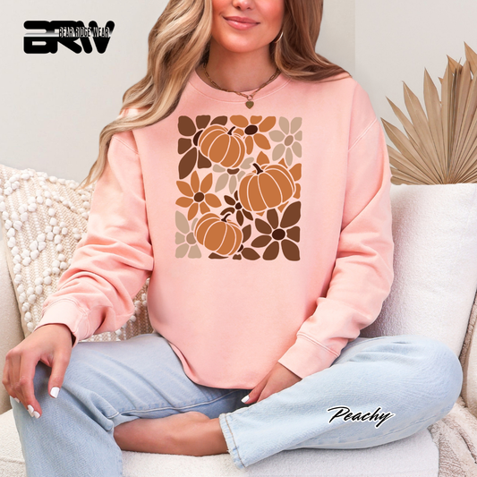 Person wearing a pink sweatshirt with pumpkin and leaf pattern, sitting on a couch.