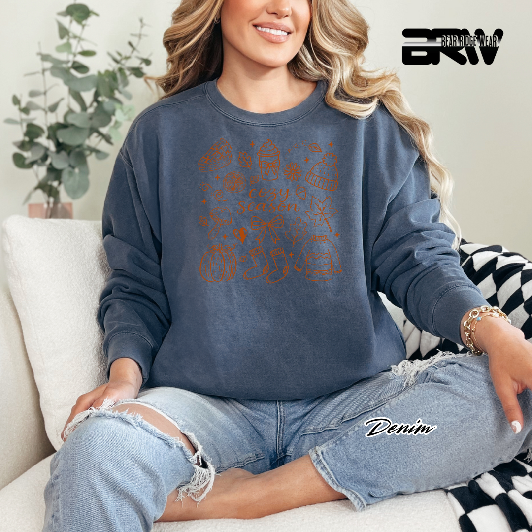 Woman wearing a blue sweatshirt with text and graphics, sitting on a couch.