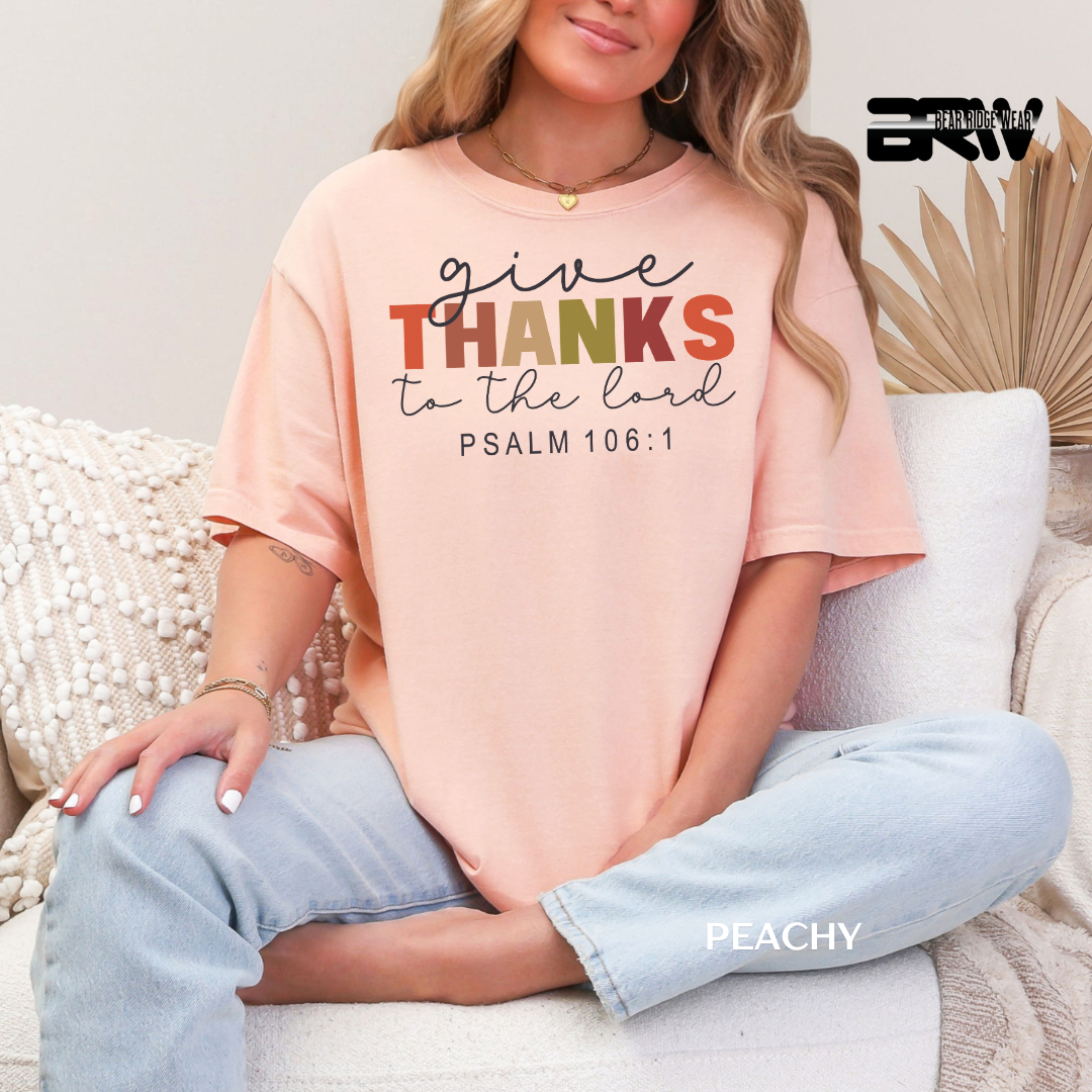Person wearing a peach t-shirt with 'give THANKS to the lord PSALM 106:1' text, sitting on a couch.