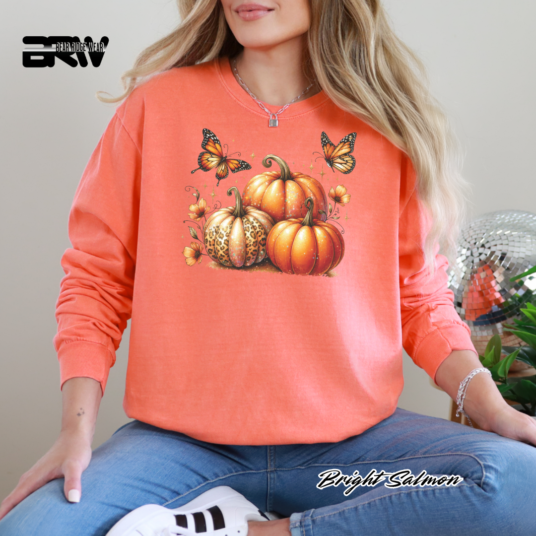 Person wearing a bright salmon-colored sweatshirt with pumpkins and butterflies design.