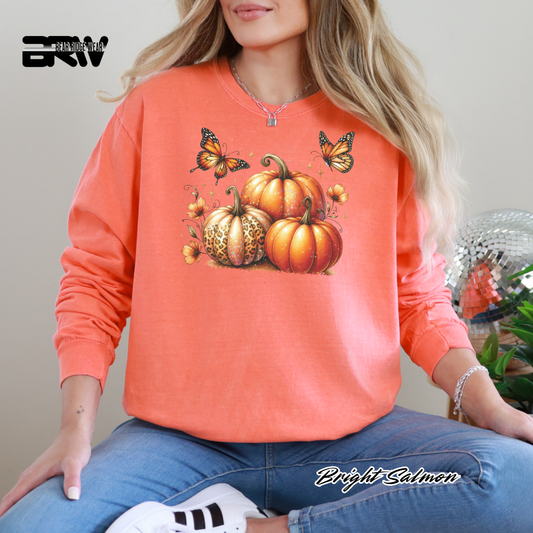 Person wearing a bright salmon-colored sweatshirt with pumpkins and butterflies design.