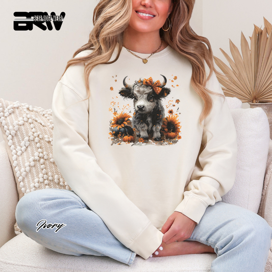 Person wearing a white sweatshirt with a cow design, sitting on a couch.