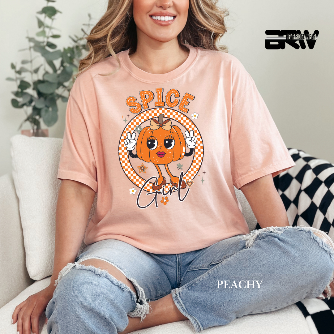 Person wearing a peach t-shirt with a pumpkin graphic and 'Spice Girl' text, sitting on a couch.